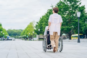 Una mujer en silla de ruedas y una mujer con delantal para cuidar al aire libre