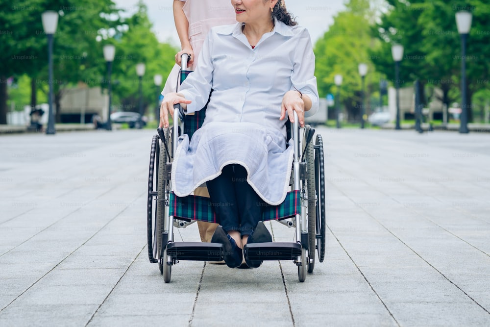 Uma mulher em uma cadeira de rodas e uma mulher em um avental para cuidar ao ar livre