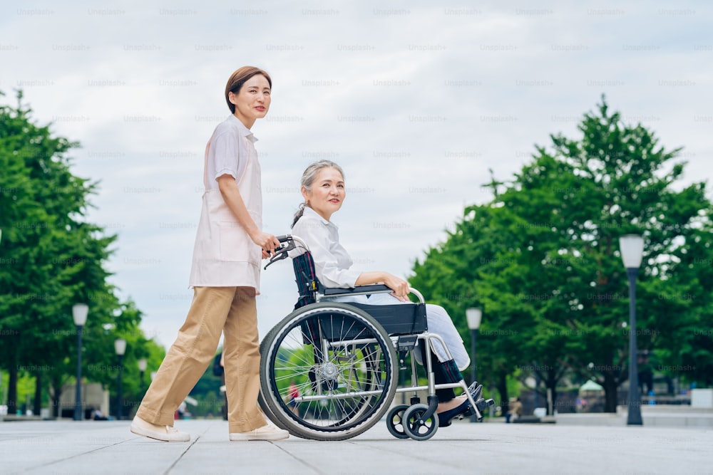 A woman in a wheelchair and young woman in an apron to care for outdoors