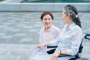 Uma mulher em um avental conversando com uma mulher idosa ao ar livre