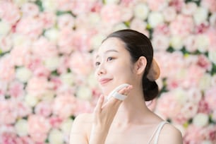 顔の皮膚にパフを塗るアジア人(日本人)の若い女性