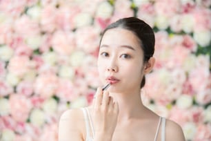 Mulher jovem asiática (japonesa) colocando batom vermelho em seus lábios