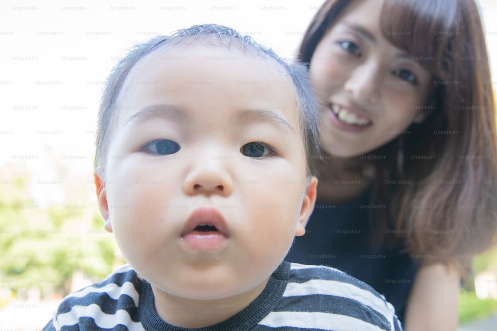 Two year old boy and his mother playing in the park on a sunny day