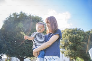 Two year old boy and his mother playing in the park on a sunny day