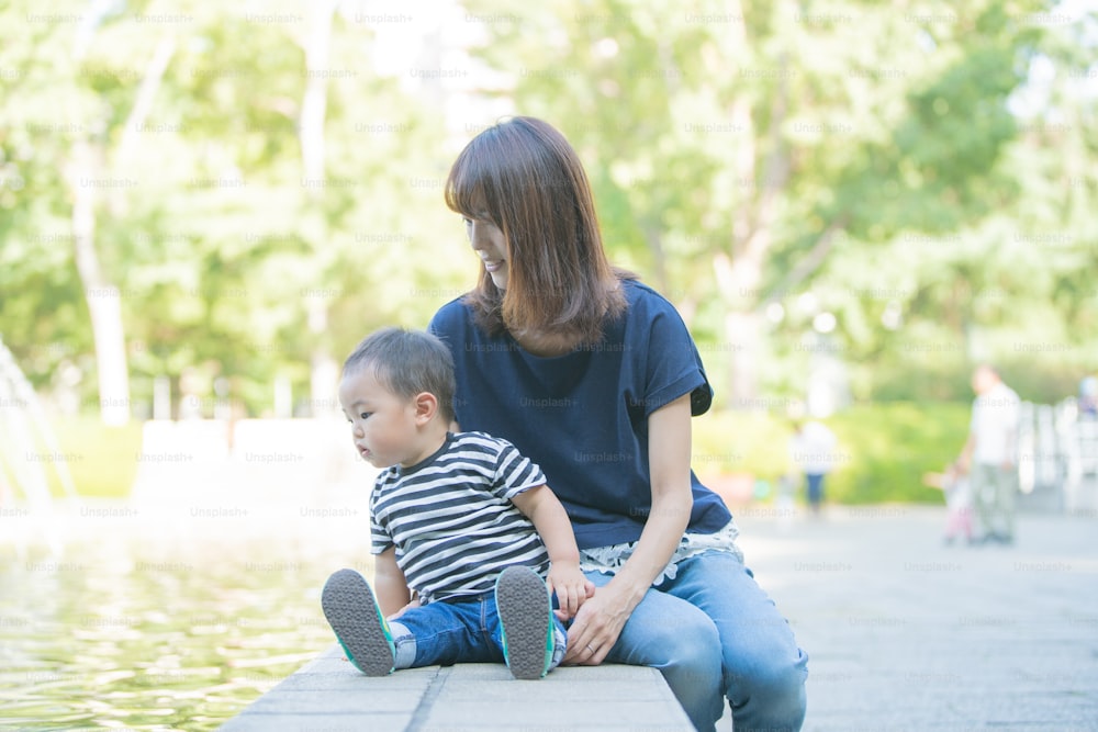 Two year old boy and his mother playing in the park on a sunny day