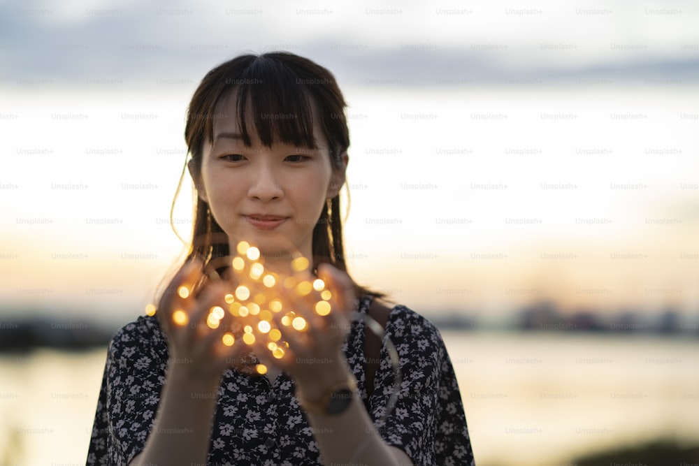 Joven asiática envolviendo una luz de iluminación con ambas manos
