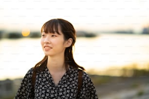 portrait of asian young woman standing by the sea in evening