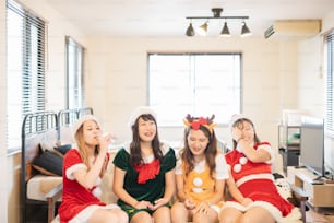 Mujeres jóvenes asiáticas vistiendo disfraces navideños y teniendo una fiesta