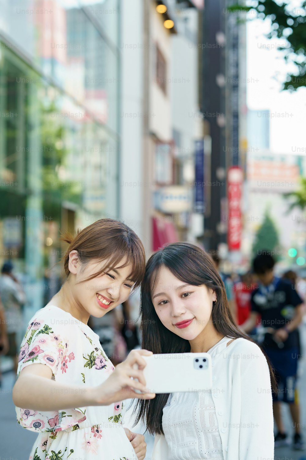 Two young women taking selfies in the city