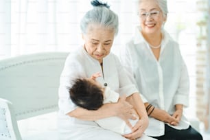Mujeres mayores abrazando a un bebé recién nacido en la habitación