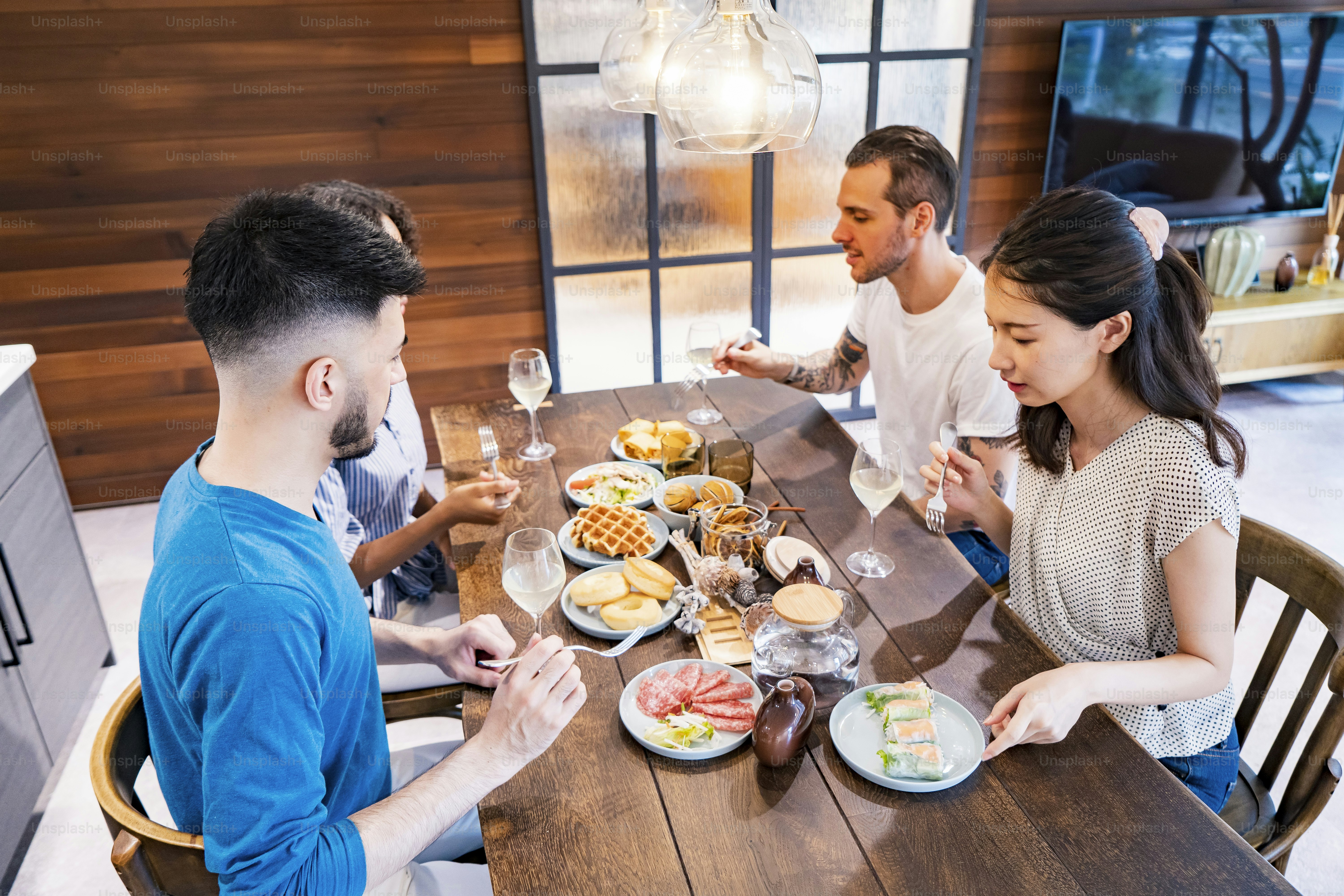 Scene of a home party where men and women surround the dining table