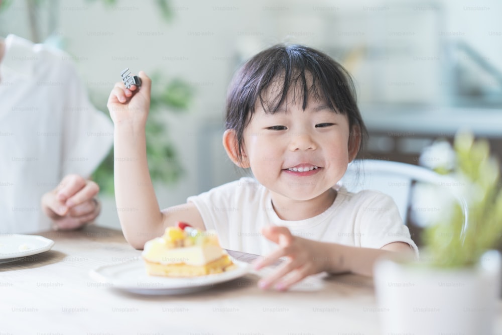 Maman et fille asiatiques mangeant un gâteau à table à manger à la maison