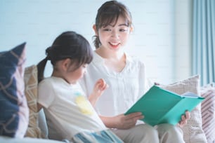 Mother and daughter sitting on the sofa and reading a picture book