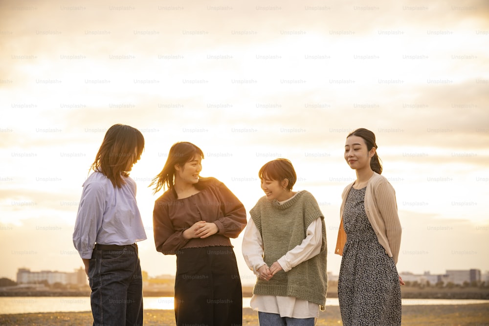 황혼에 행복하게 이야기하는 네 명의 아시아 젊은 여성