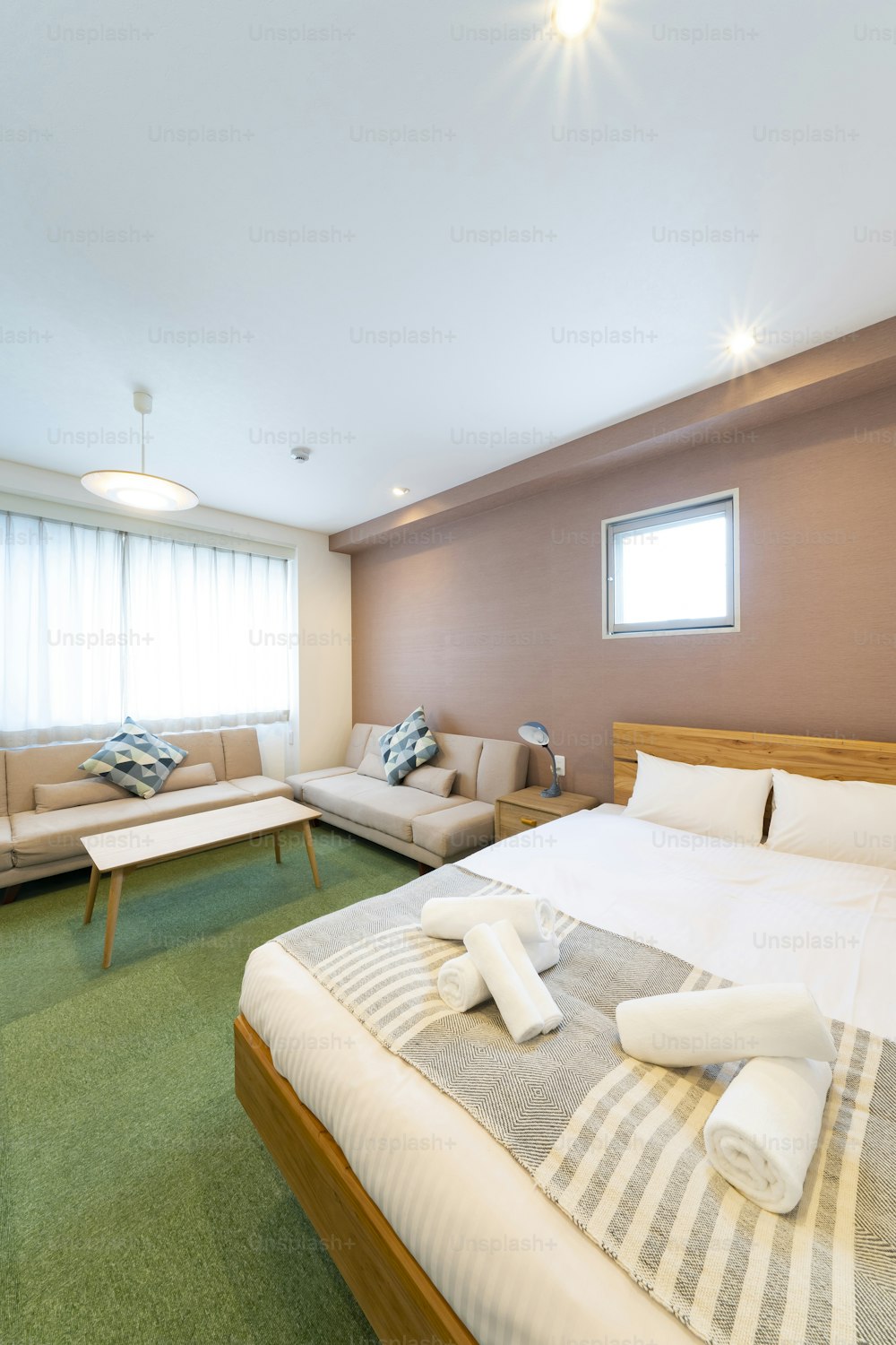 Quarto de hotel com sofá, almofadas, mesa e cama