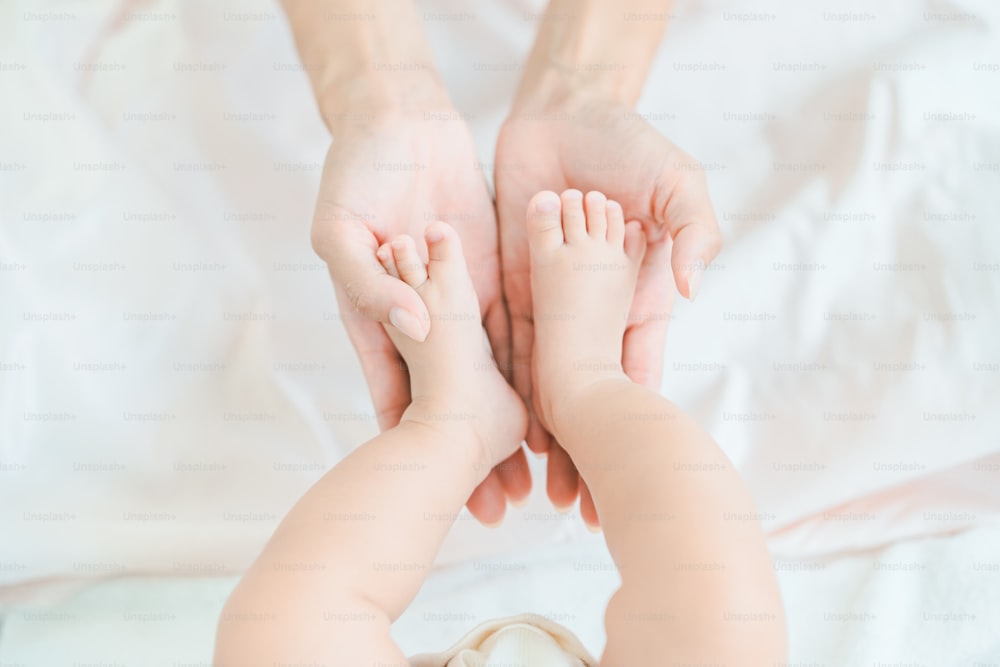 Mother's hands supporting the baby's feet in the room