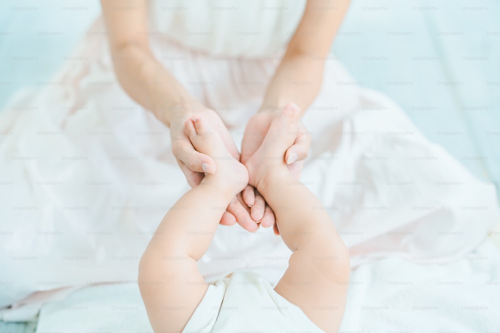 Mutterhände, die die Füße des Babys im Raum stützen