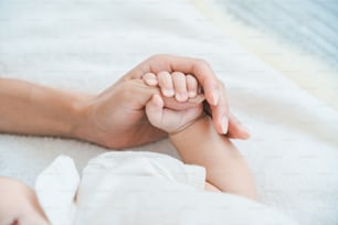 Mother's hand supporting her baby's hand