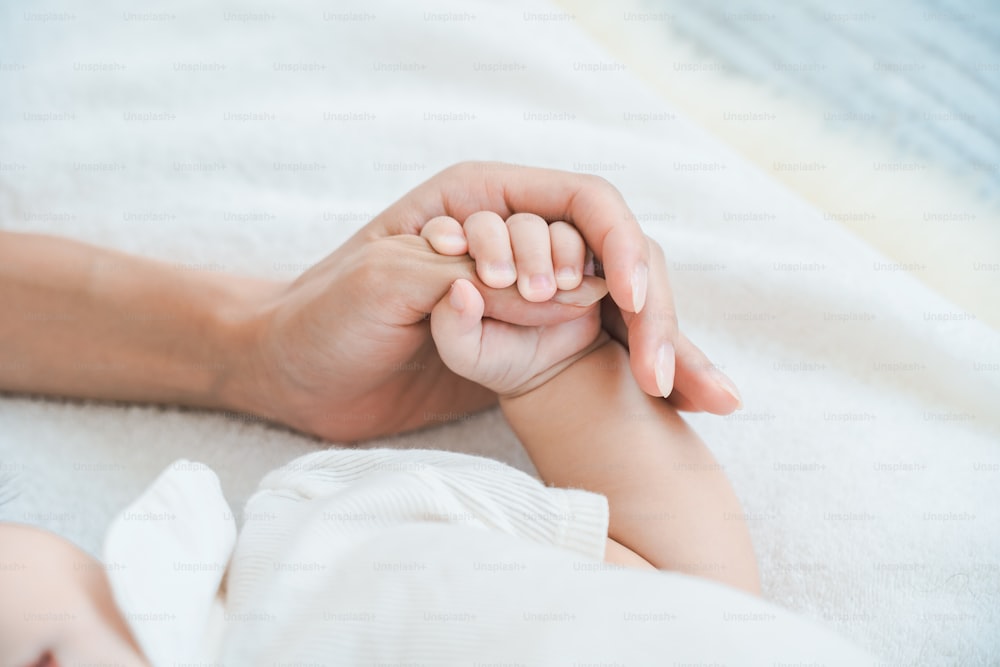 Die Hand der Mutter stützt die Hand ihres Babys