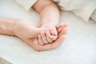 Mão da mãe apoiando a mão do bebê