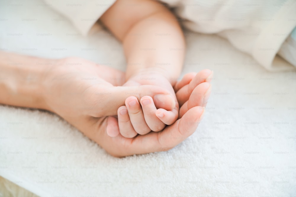 Mother's hand supporting her baby's hand