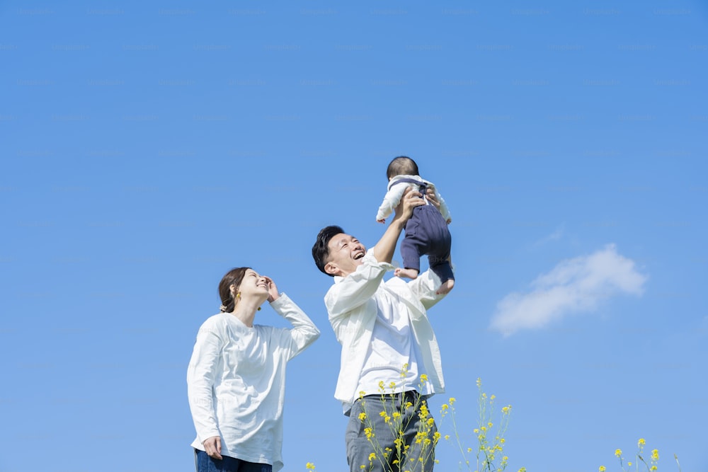 Eltern halten ihr Baby hoch unter dem blauen Himmel