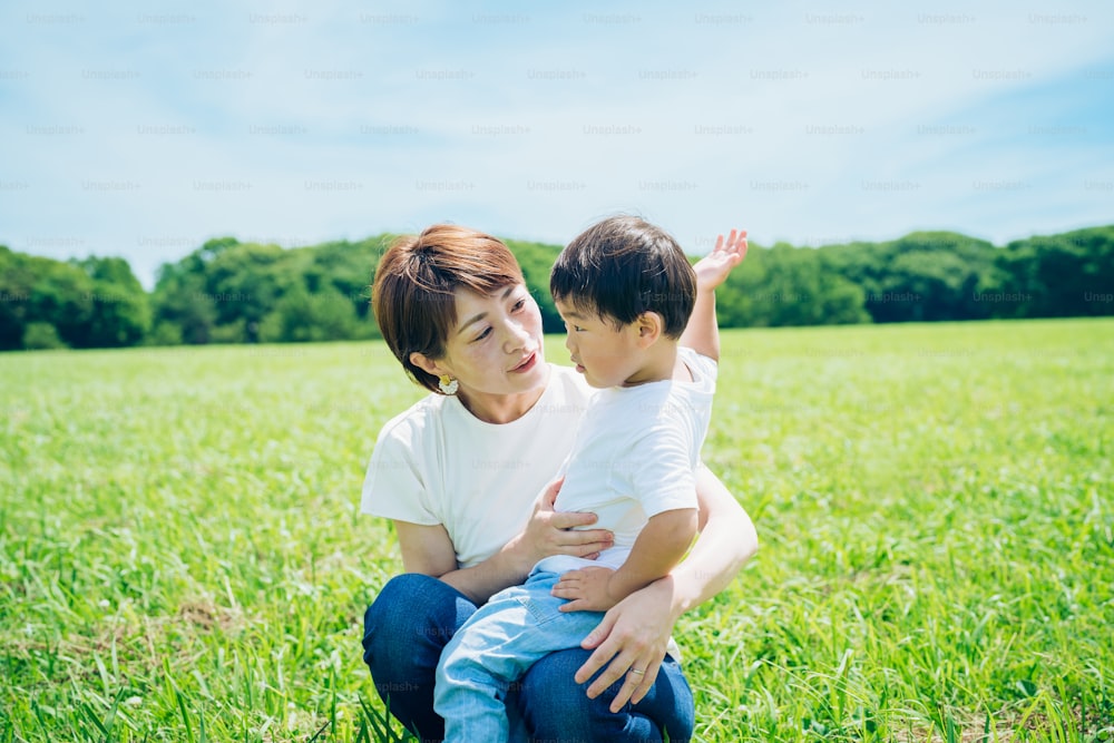 Mutter umarmt ihren Jungen auf der Grünfläche an einem schönen Tag
