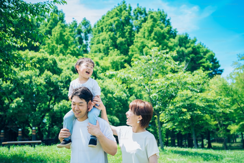 Parents and child playing happily while piggybacking in the park