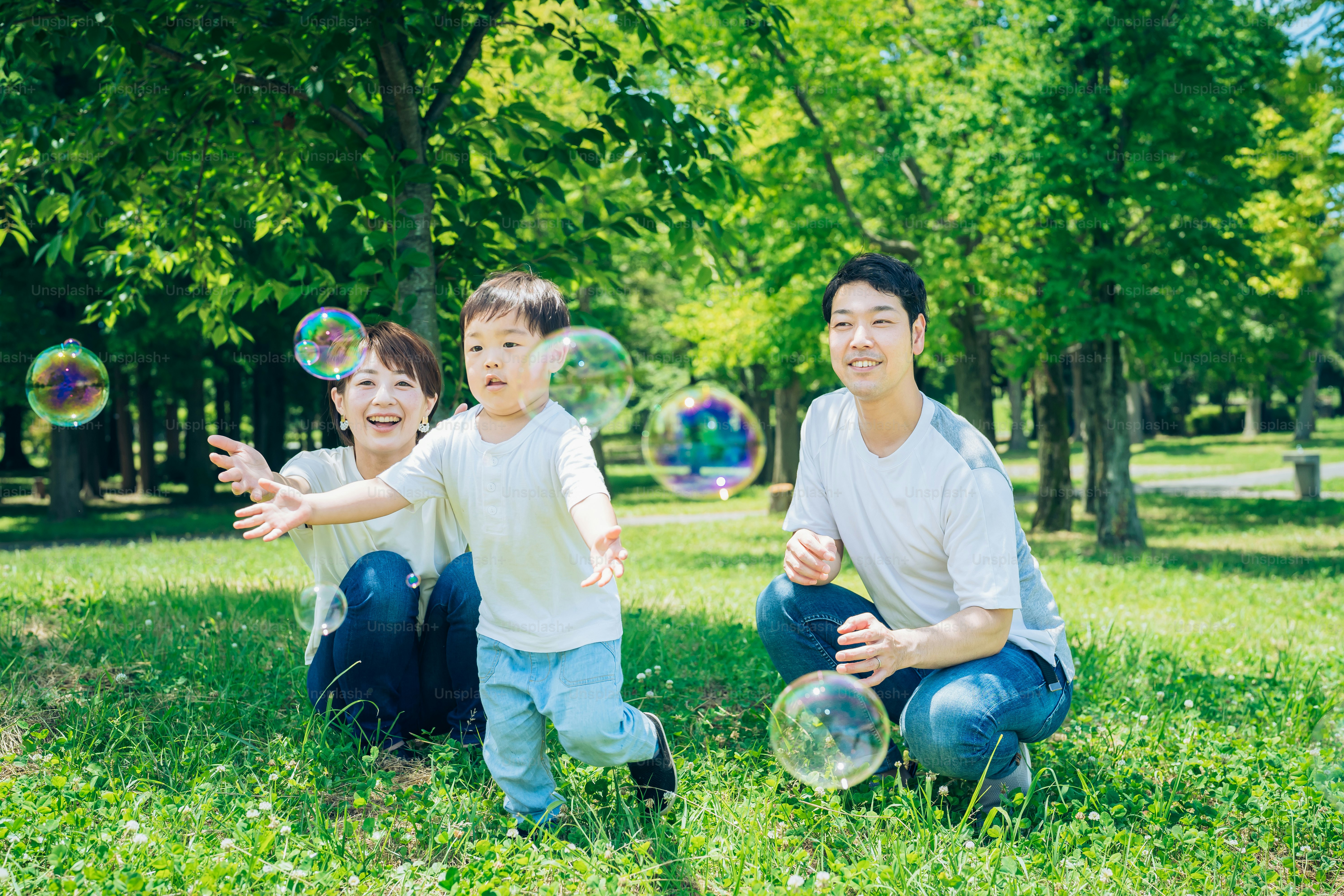 Genitori e il loro bambino che giocano con bolle di sapone al parco