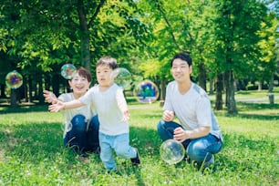 Genitori e il loro bambino che giocano con bolle di sapone al parco