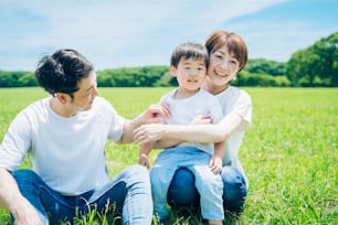Parents and their child sitting on a sunny green space on fine day