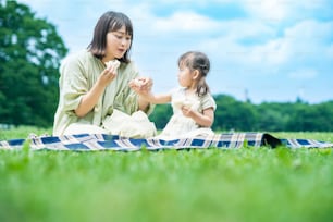 mother and her daughter eating sandwiches in the park on fine day