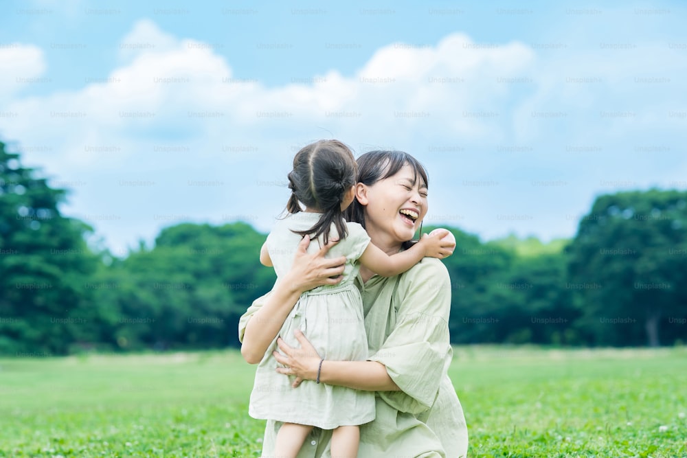 아시아의 젊은 엄마와 그녀의 �딸이 공원에서 포옹