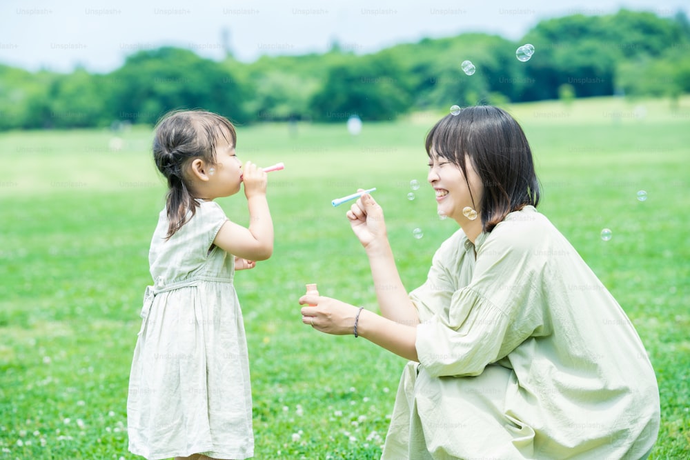 Une mère et sa fille jouent avec des bulles de savon dans le parc