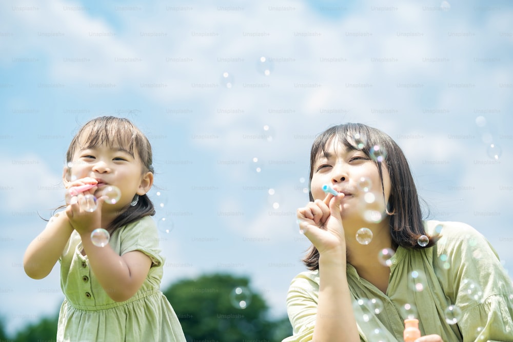 Madre e la sua figlia che giocano con le bolle di sapone nel parco