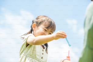 mother and her daughter playing with soap bubbles in the park