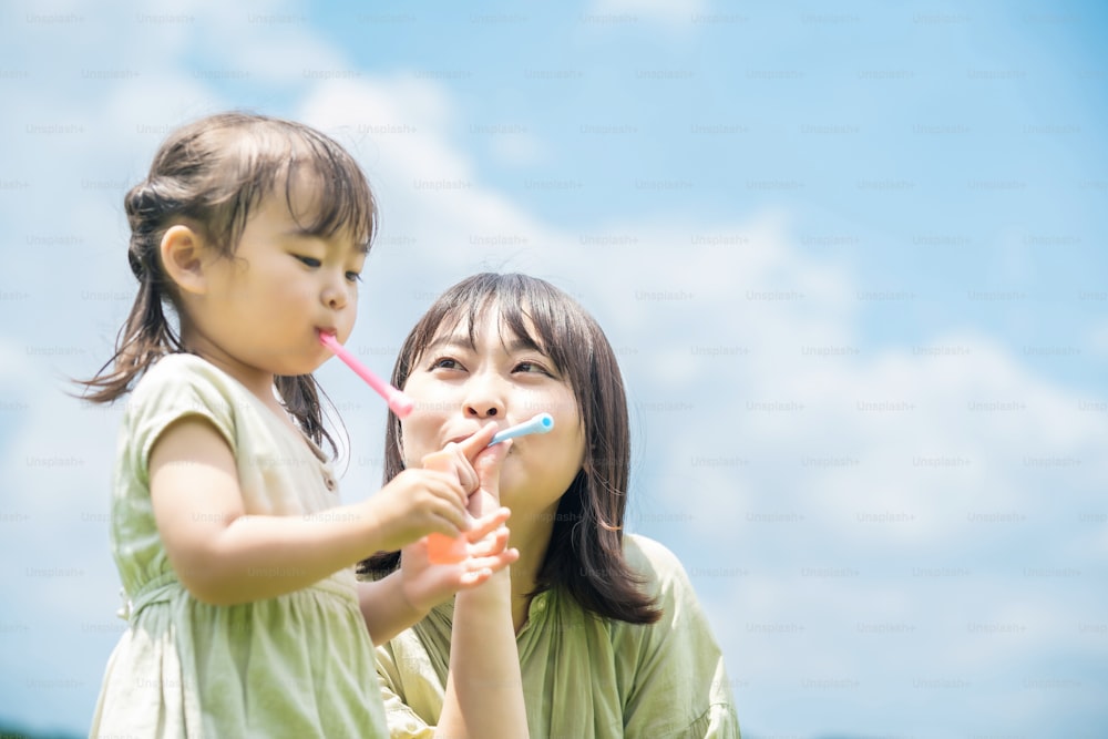 Mutter und ihre Tochter spielen mit Seifenblasen im Park