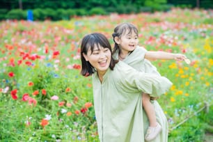 mother and her daughter strolling in the flower field at the park