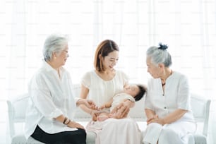 Asian mom holding a baby and two senior women