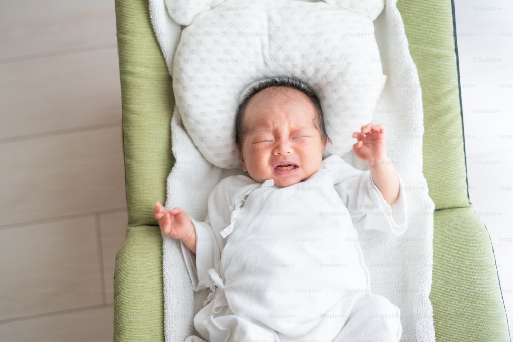 Neugeborenes asiatisches (japanisches) Baby auf dem Bett (0 Jahre 0 Monate alt)