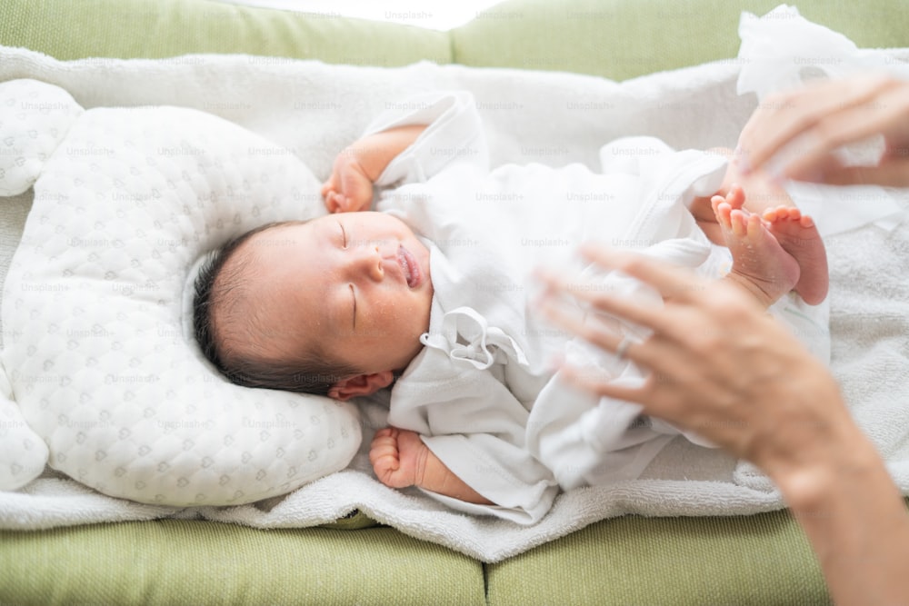 Mère changeant bébé (0 an, 0 mois) couche d’asiatique (japonais)