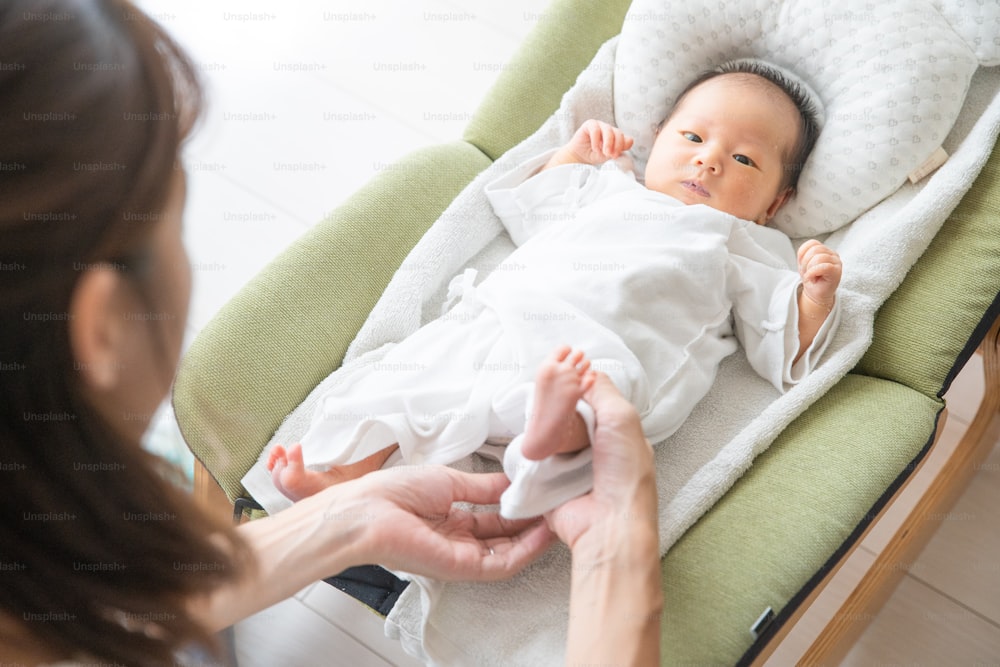 Madre che cambia bambino (0 anni, 0 mesi) pannolino di asiatico (giapponese)