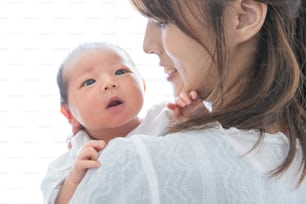 Eine Mutter, die ein asiatisches (japanisches) Neugeborenes trägt (0 Jahre alt, 0 Monate alt)