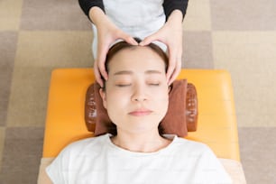 Asian female practitioner massaging the head and face of female patient