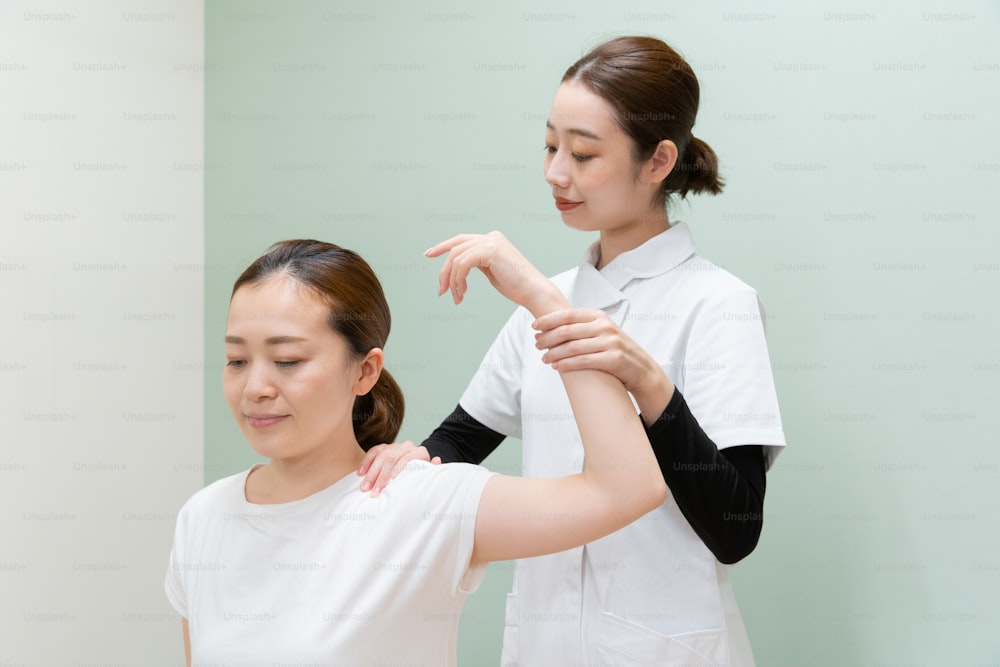 Practicante asiática masajeando hombros y cuello de paciente femenina