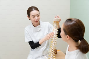 Asian female practitioner listening to female patient's symptom and explaining treatment method