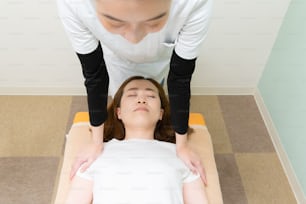 女性患者の肩と首をマッサージするアジアの女性開業医