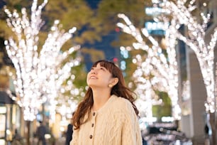 Una joven asiática (japonesa) observando las iluminaciones que colorean la ciudad nocturna