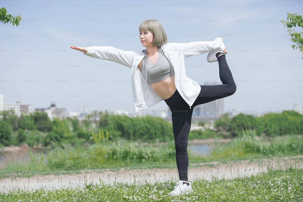 Asian young woman doing stretching exercise in urban green space