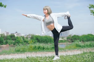 Asian young woman doing stretching exercise in urban green space